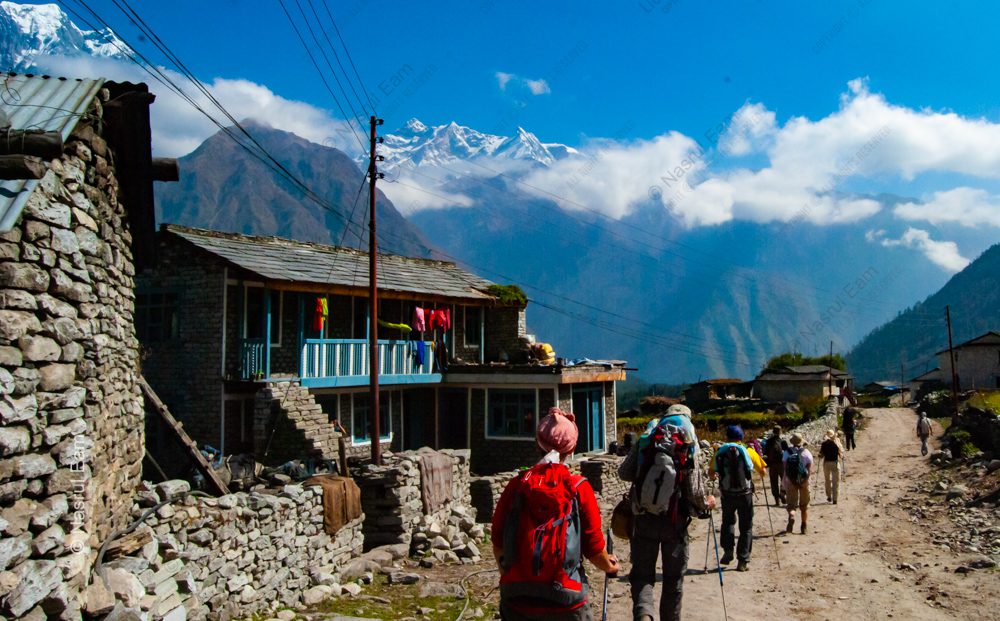High Mountain Passage: Trekkers on a Stone-Lined Path to Distant Peaks