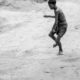 A Boy Tossing a Stone on a Dusty Plain - Fine Art Photography Print, Limited Edition Photography, Museum-Quality Photography, Contemporary Art Photography, Photography for Collectors