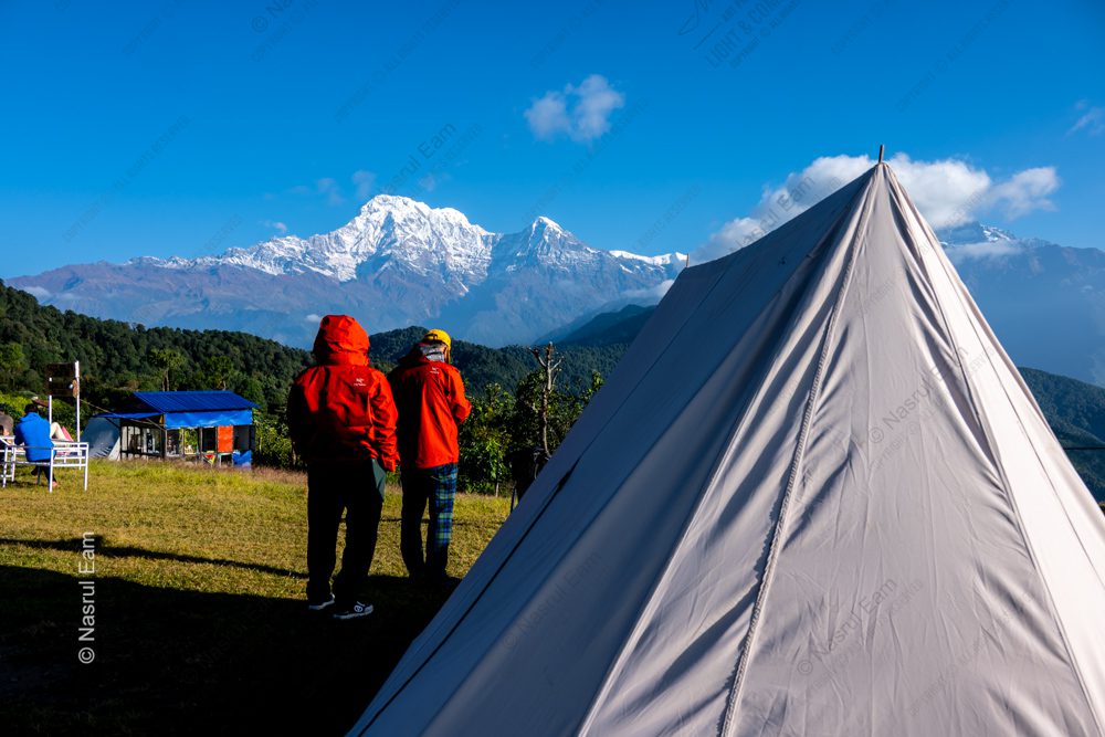 Two Figures and a Tent Facing Majestic Snow-Capped Peaks