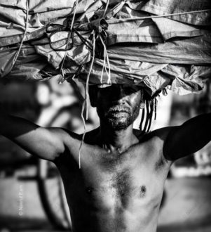 The Porter Under a Sunlit Burden - Visual Storytelling in Photography Books, Documentary Photography Techniques, Monochrome Fine Art Photography, Photography Composition Masterclass, Human Spirit Photography, Photographic Endurance Study