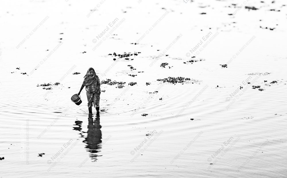 Solitary Journey with Bucket Across Reflective Water