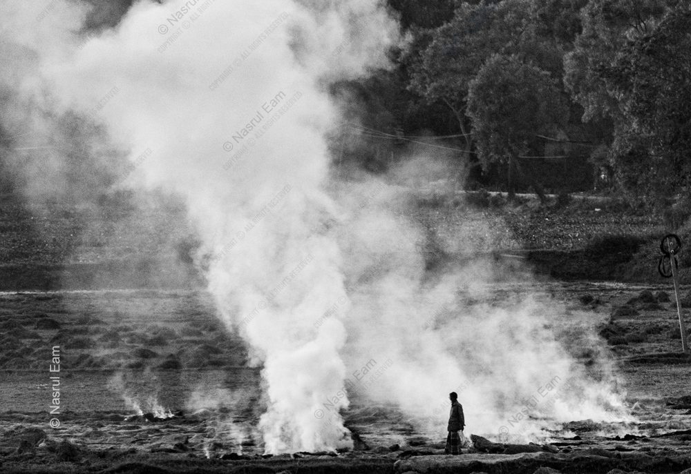 The Field's Breath: A Solitary Figure Amidst Rising Smoke