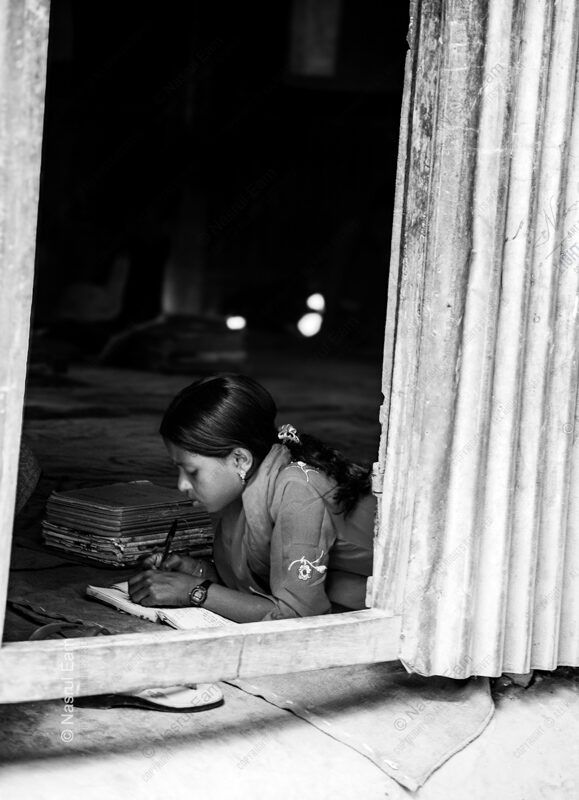 Girl Writing Beside Stacked Notebooks