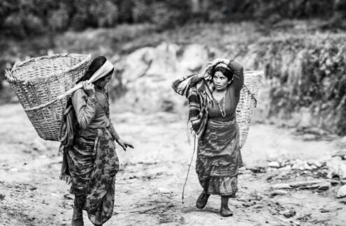 Two Women Bearing Loads on a Hillside Path