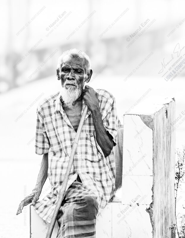 Elder Seated with Bamboo Staff on White Masonry - Elder Seated with Bamboo Staff on White Masonry, Nasrul Eam monochrome portrait, limited edition fine art print, artistic portrait photography, black and white photography print, fine art cotton rag print