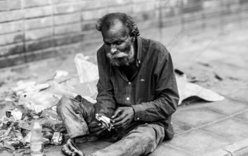 Man Unwrapping Sustenance by the Brick Wall