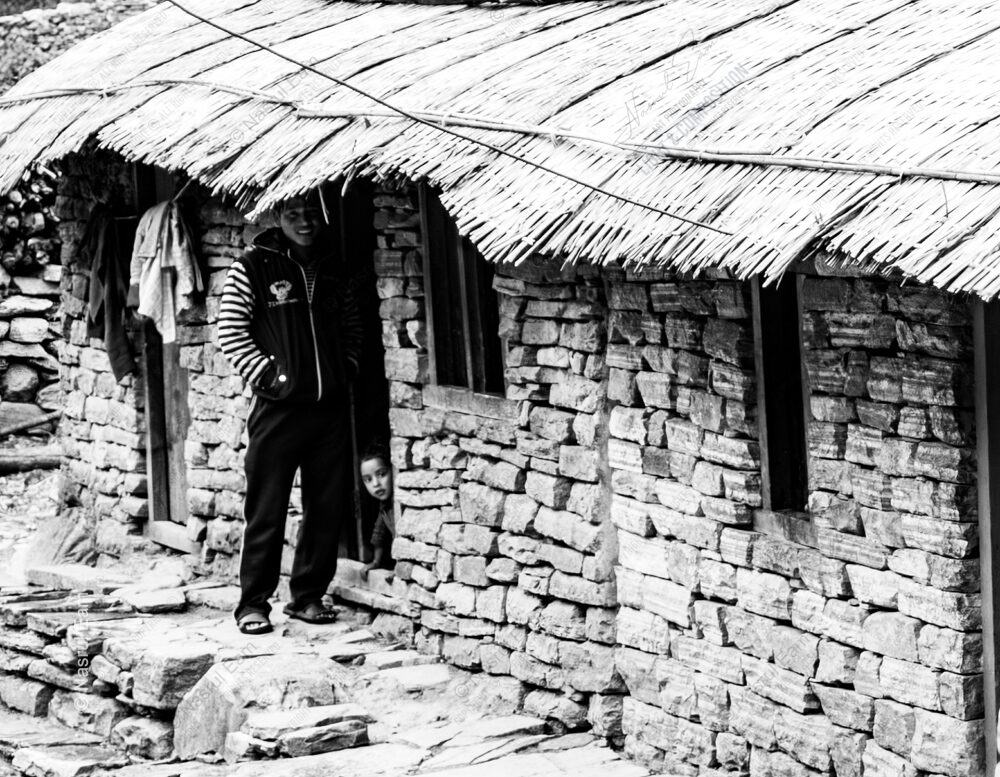 Stone Wall, Thatch Roof, and Peeking Child - Stone Wall Thatch Roof Peeking Child, Nasrul Eam fine art print, Himalayan