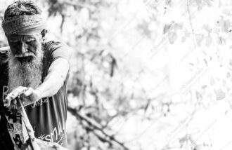 Elder with Wrapped Headband Gripping Wood - Elder with Wrapped Headband Gripping Wood, Nasrul Eam fine art print, monochrome portrait photography