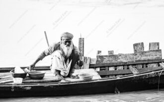Elderly Boatman Crouched on Plank Deck - Elderly Boatman, weathered boatman print, Nasrul Eam photography, monochrome fine art print, limited edition art print, documentary portraiture