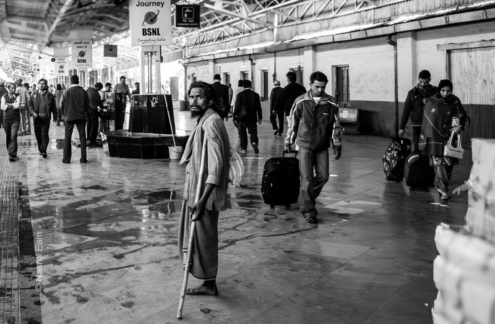 A Man with a Crutch on a Crowded Platform