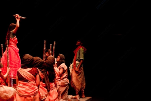 Performers in Crimson and Gold on a Darkened Stage