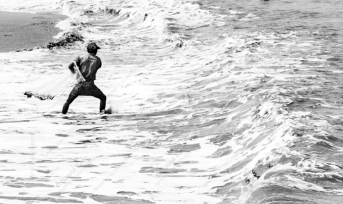 A Fisherman Casting His Net into the Surf