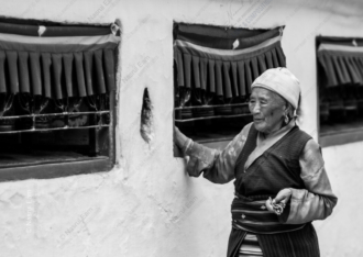 An Elder with Mala Beads by a Whitewashed Wall