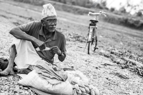 Elderly Merchant Resting on a Pebble Shore