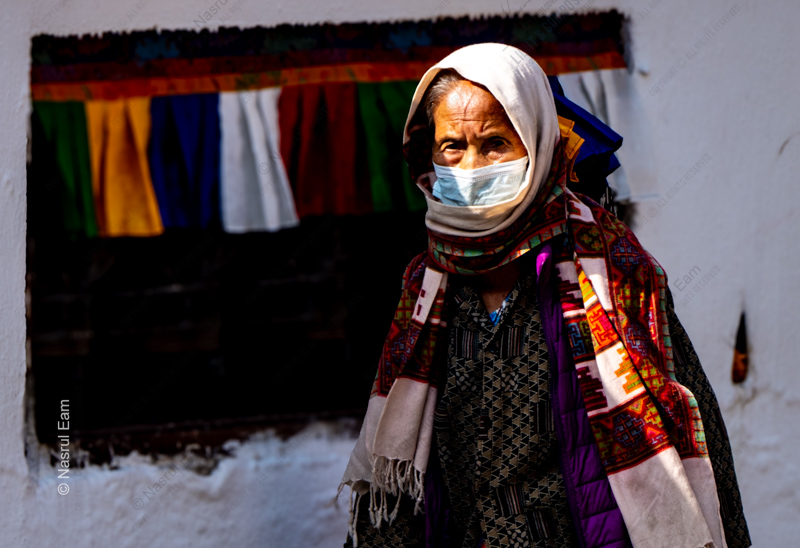 Woman with Mask Before Prayer Flags