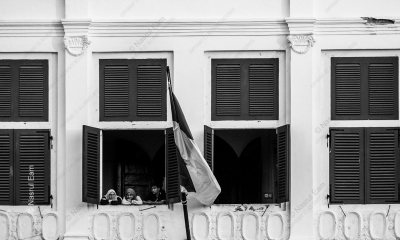 Three Youths at an Open Window with Flag