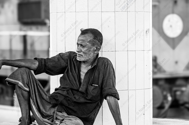 Man Resting Against a White Pillar