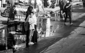 Boy and Women at the Roadside Water - street photography, urban photography, documentary photography, visual storytelling, fine art photography, light and shadow