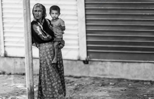 Woman Holding a Child by a Shuttered Wall