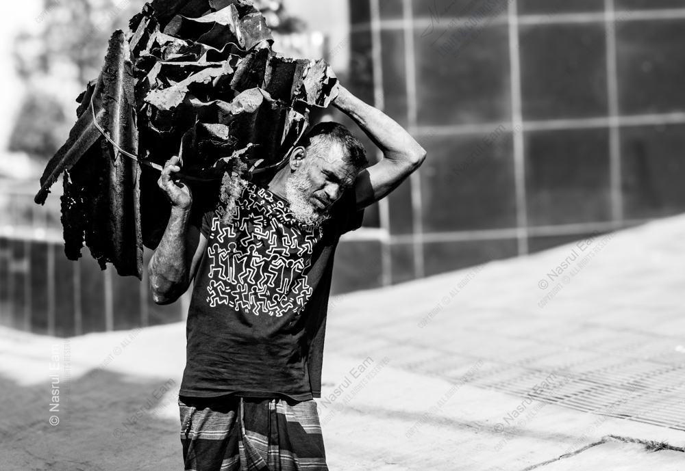 A Man Beneath the Weight of Scrap Metal