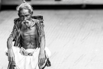 An Elder Seated on the Pavement