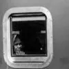 A Traveler's Face in a Riveted Window
