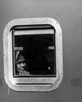 A Traveler's Face in a Riveted Window