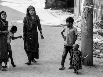 A Woman's Watchful Gaze and Children's Play on a Dusty Lane