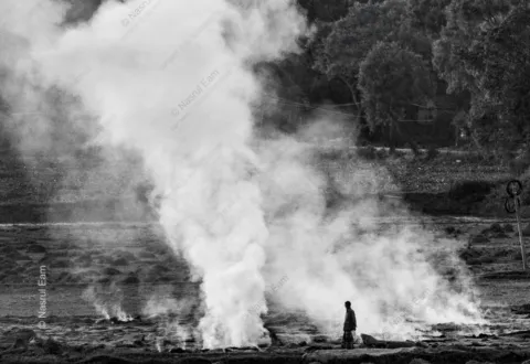 The Field's Breath: A Solitary Figure Amidst Rising Smoke